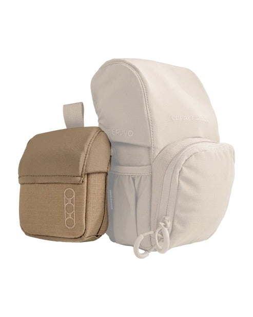 Auf weißem Hintergrund sind zwei EBERLESTOCK Mag-Free Rangefinder Pouches abgebildet: eine beigefarbene mit Frontklappe und Schlaufe, die andere hellgrau mit Reißverschlüssen und Seitentaschen - ideal für Outdoor-Ausrüstung oder als Jagdtasche.