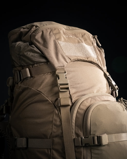 Der EBERLESTOCK Brute 6500, ein großer, hellbrauner taktischer Rucksack mit mehreren Fächern, Schnallenriemen und Klettverschluss-Patch-Panel, ist vor einem dunklen Hintergrund abgebildet - perfekt als Expeditionsrucksack für anspruchsvolle Einsätze.