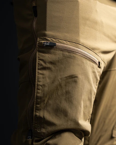 Nahaufnahme der EBERLESTOCK Deadwood Pant - Black, aus Stretch-Nylon, mit einer Oberschenkeltasche mit Reißverschluss und detaillierten Nähten mit Schatten, die die Textur des Stoffes und die Nähte akzentuieren.