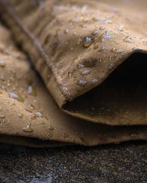 Nahaufnahme des schwarzen, wasserabweisenden Gewebes der EBERLESTOCK Deadwood Pant - Black, mit Wassertropfen, die auf der Oberfläche abperlen und die schützenden Eigenschaften dieser Hose gegen Feuchtigkeit zeigen.