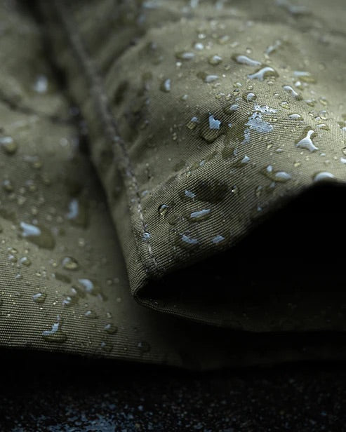 Eine Nahaufnahme von coyote-braunem Stoff mit Wassertropfen auf der Oberfläche, die die EBERLESTOCK Camas Pro Pant - Coyote Brown und ihre effektiven wasserabweisenden Eigenschaften hervorheben.