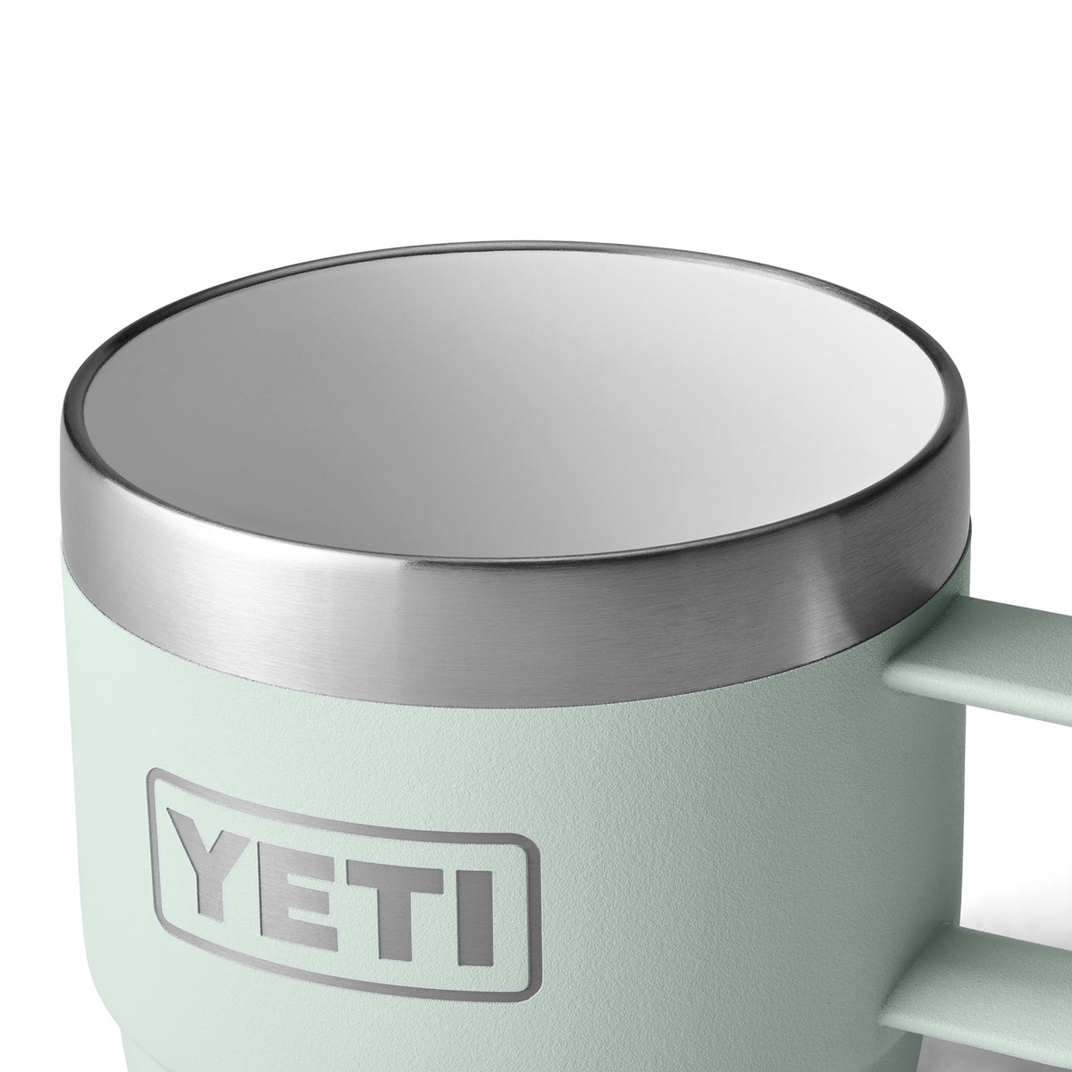Eine Nahaufnahme einer hellblauen YETI® Espresso-Tasse Rambler 6 Oz (2er Pack) - Ridgeline mit Vakuumisolierung, Edelstahlrand und Griff. Das YETI-Logo ist an der Seite sichtbar, und das weiße Innere kontrastiert mit dem Edelstahlbecher.