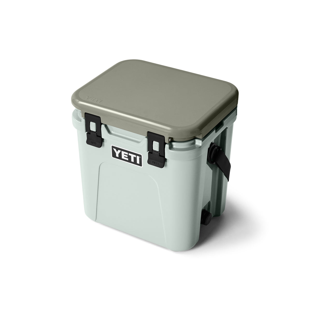 Die YETI® Kühlbox Roadie 24 - Ridgeline ist eine hellgraue Kühlbox mit hellbraunem Deckel, schwarzen Verschlüssen und weißem YETI-Logo - perfekt für Camping mit fortschrittlicher PermaFrost Isolierung. Abgebildet auf weißem Hintergrund.