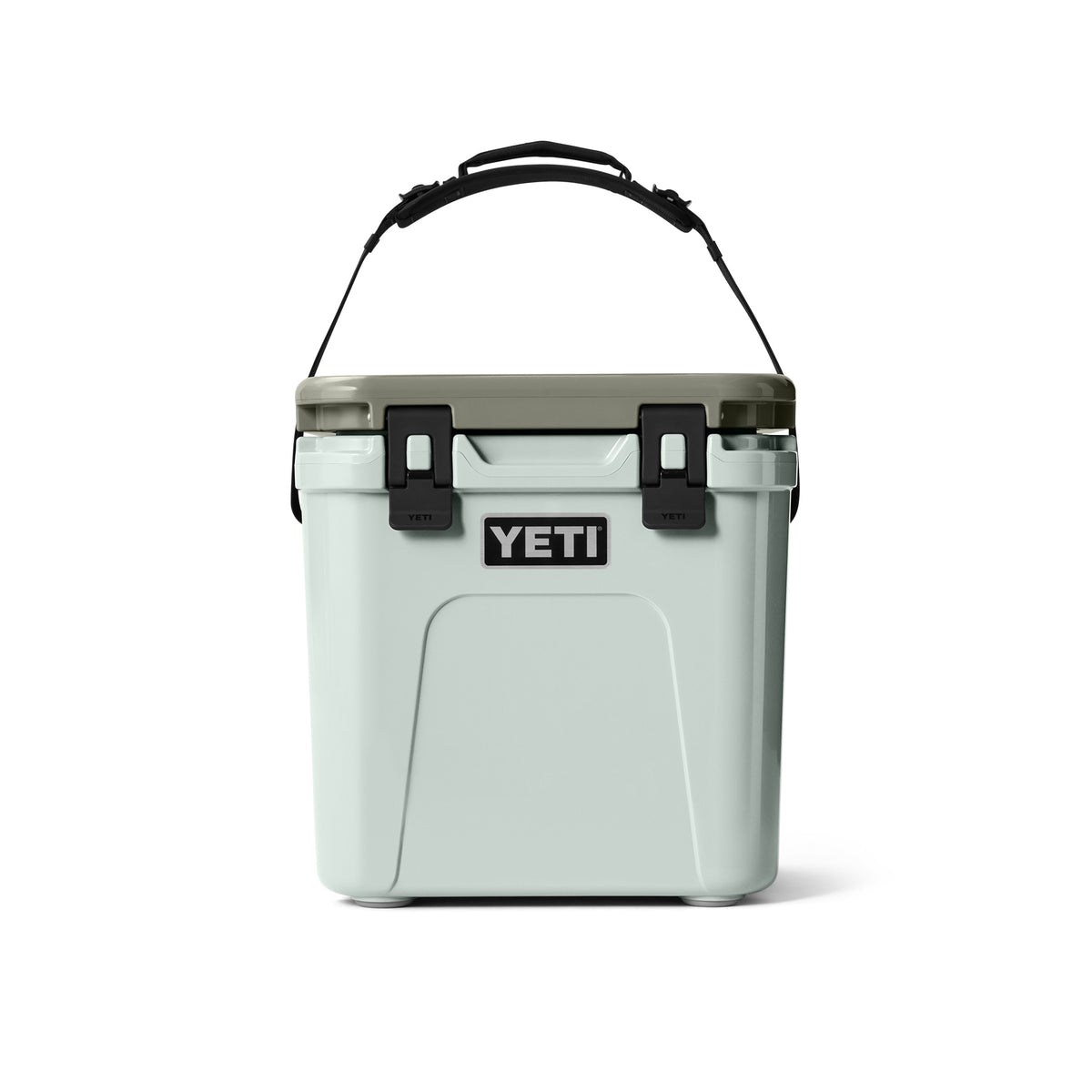 Eine YETI® Kühlbox Roadie 24 - Ridgeline mit hellblauem Korpus, dunkelgrünem Deckel, schwarzen Verschlüssen und Griff, die für den Einsatz beim Camping konzipiert ist, wird vor einem schlichten weißen Hintergrund gezeigt.