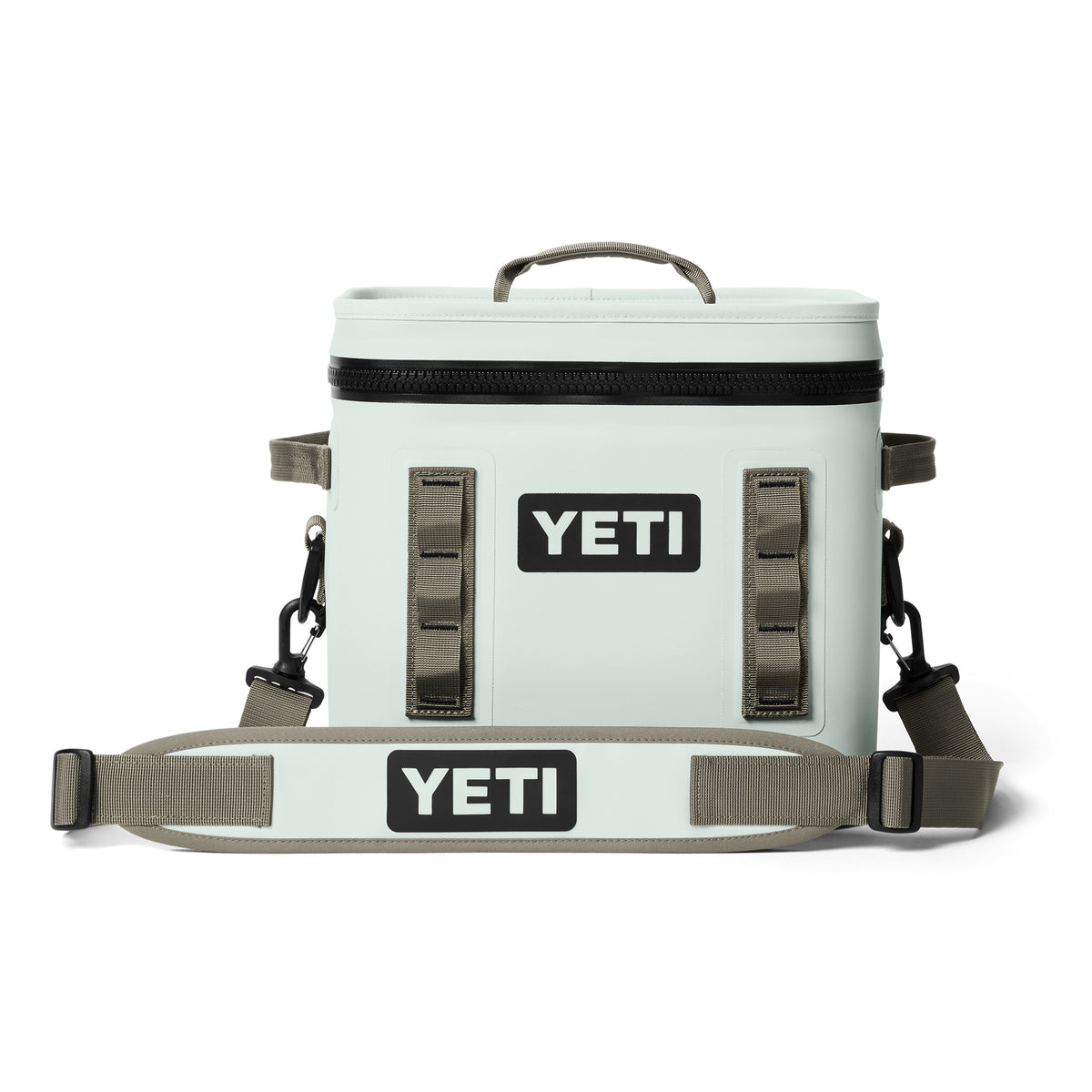 Die YETI® Kühltasche Hopper Flip® 12 - Ridgeline ist eine hellgraue Kühltasche mit schwarzem Reißverschluss, hellbraunen Seitengriffen, einem verstellbaren Schultergurt und dem YETI-Logo in Schwarz und Weiß.
