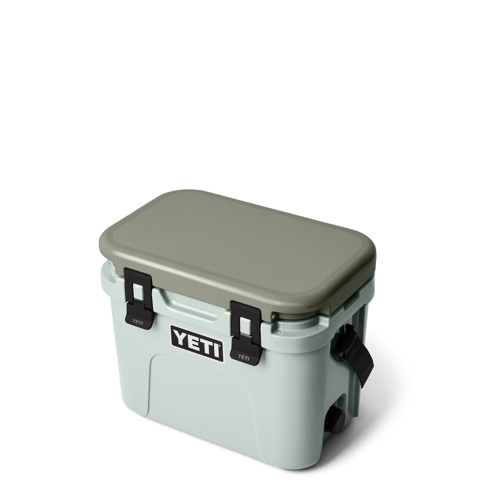 Eine YETI® Kühlbox Roadie 15 - Ridgeline in Hellgrau mit passendem Deckel, schwarzen Seitengriffen und schwarzen Verschlüssen wird vor einem weißen Hintergrund gezeigt.