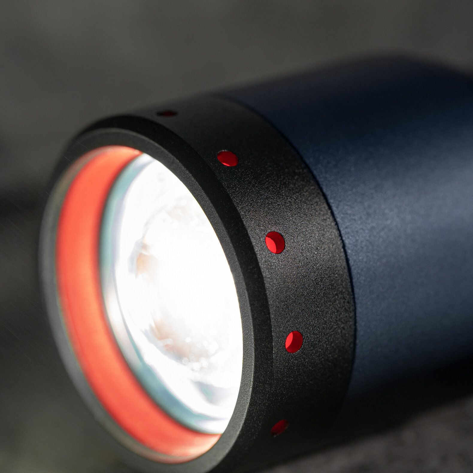 Nahaufnahme der LEDLENSER Taschenlampe P7R - 25 Jahre Edition, einer schwarz-blauen Taschenlampe mit roten Akzentlöchern und einem hellen weißen Lichtstrahl, die ihr besonderes 25-jähriges Jubiläum feiert.