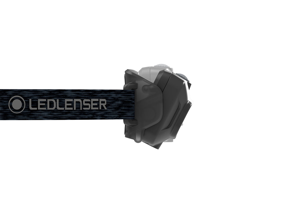 Eine schwarze LEDLENSER Stirnlampe HF4R Core mit einem strukturierten Band mit der Aufschrift "LEDLENSER", von der Seite auf weißem Hintergrund dargestellt.