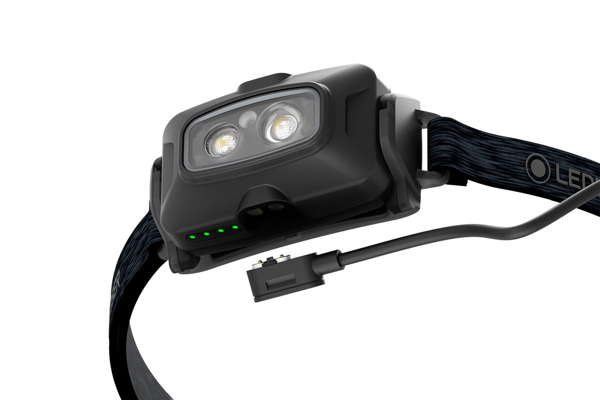 Nahaufnahme der LEDLENSER Ledlenser Stirnlampe HF4R Core in Schwarz, mit 500 Lumen, verstellbarem Gurt, zwei Lichtlinsen, vier grünen Kontrollleuchten und einem abnehmbaren magnetischen Ladekabel an der Seite.