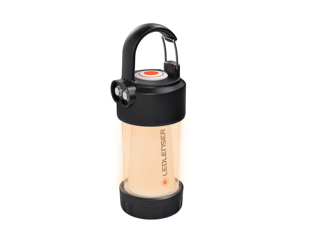 Die LEDLENSER ML4 WL Outdoor-Campinglampe hat einen schwarzen Griff und Sockel, einen transparenten zylindrischen Körper, der mit warmweißem Licht leuchtet, und das LEDLENSER-Logo, das senkrecht auf die Seite gedruckt ist.
