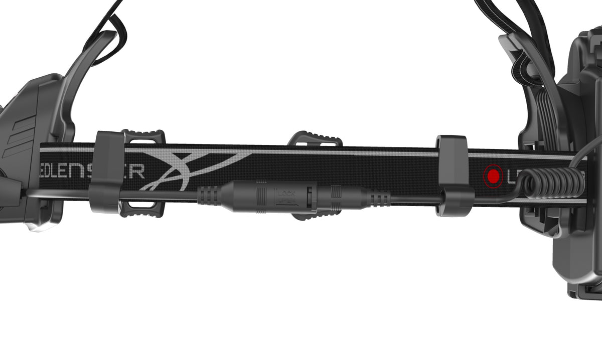 Nahaufnahme eines schwarzen Armbands der LEDLENSER Ledlenser Stirnlampe H14R.2 mit Anschlüssen, Kabeln und einem SELECT-gekennzeichneten Abschnitt mit einer X-Grafik. Der weiße Hintergrund hebt die Merkmale dieses Armbands für elektronische Geräte hervor.