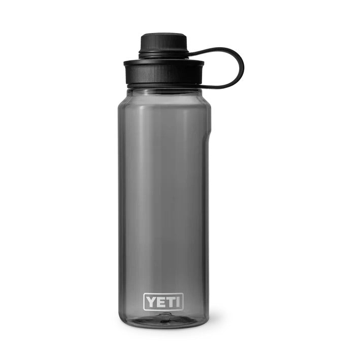 Die klargraue YETI® Yonder™ 1L Wasserflasche von YETI mit bruchfestem Design, schwarzem Schraubdeckel und Trageschlaufe steht aufrecht vor einem weißen Hintergrund.
