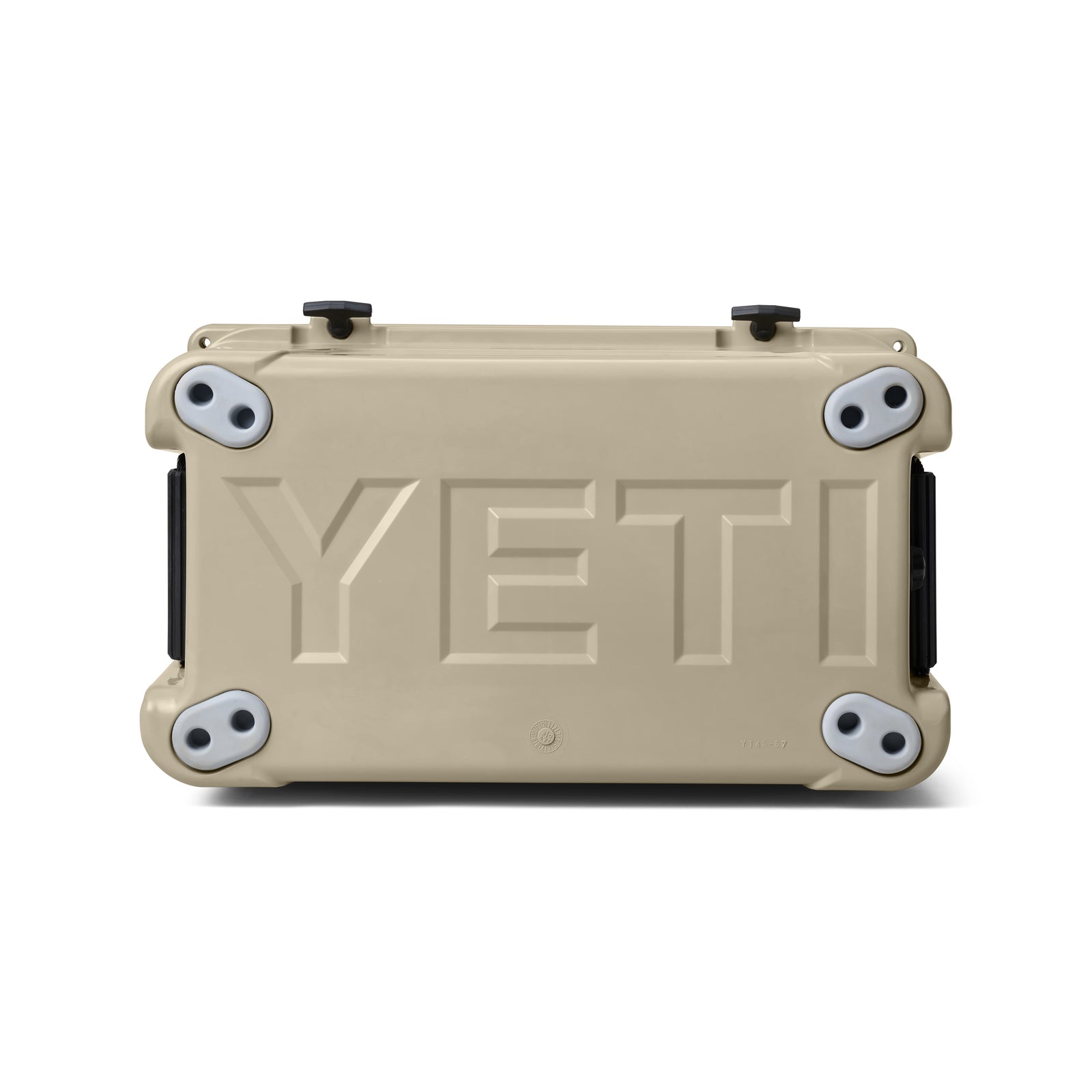 Auf der Rückseite liegt eine YETI® Kühlbox Tundra 45 - Tan, auf der das geprägte YETI-Logo zu sehen ist. Vier graue und schwarze Gummifüße betonen die robuste Kühlbox, einer an jeder Ecke.