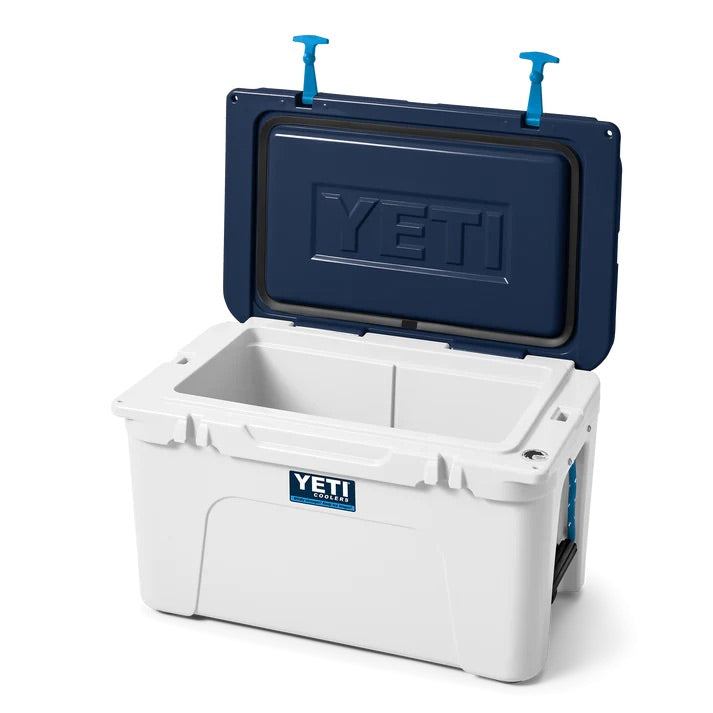 Die weiß/blaue YETI® Kühlbox Tundra 45 von YETI ist geöffnet und zeigt ihren leeren Innenraum. Der blaue Deckel hat innen zwei blaue Griffe, und das YETI-Logo ist sowohl auf der Vorder- als auch auf der Innenseite der Kühlbox zu sehen.