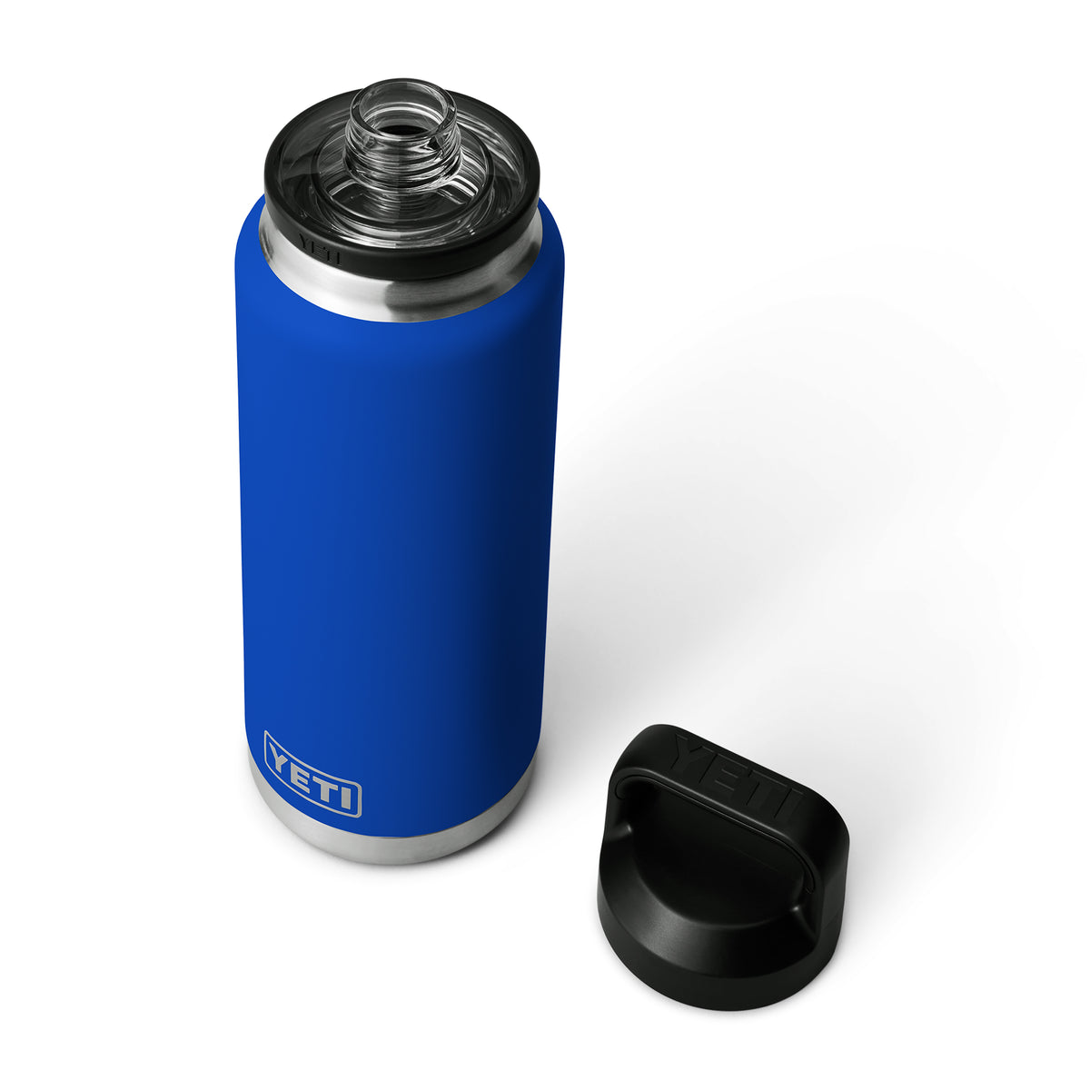 Eine YETI® Flasche Rambler 36 Oz - Royale Blue von YETI ist auf einem weißen Hintergrund abgebildet. Der schwarze Schraubdeckel wurde entfernt und daneben gelegt, wodurch das Gewinde um die Öffnung und der silberne Boden der Flasche sichtbar werden.