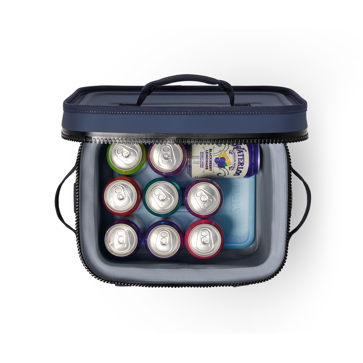 In einer geöffneten YETI® Kühltasche Hopper Flip® 12 - Navy sind neun verschiedene Limonadendosen, eine große Getränkedose und ein blauer Kühlakku fein säuberlich angeordnet.