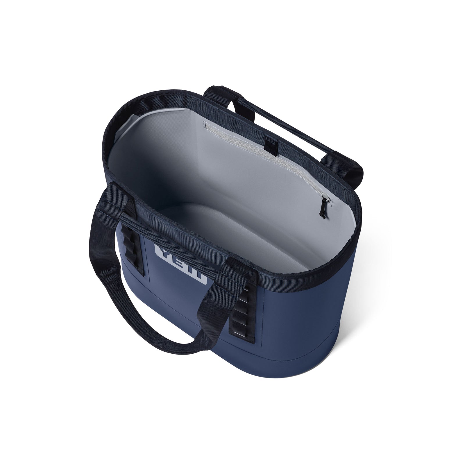 Draufsicht auf eine geöffnete YETI® Tragetasche Camino® Carryall 35 – Classic Navy, eine robuste Allzwecktasche von YETI mit schwarzen Tragegriffen und einem geräumigen, leeren Innenraum.