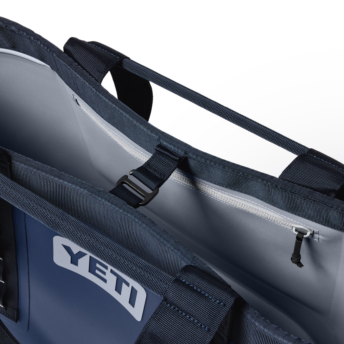 Nahaufnahme der geöffneten YETI® Tragetasche Camino® Carryall 35 – Classic Navy mit Blick auf den Innenraum, die robusten Tragegriffe, das Reißverschlussfach und das gut sichtbare YETI-Logo auf dieser wasserdichten Allzwecktasche.