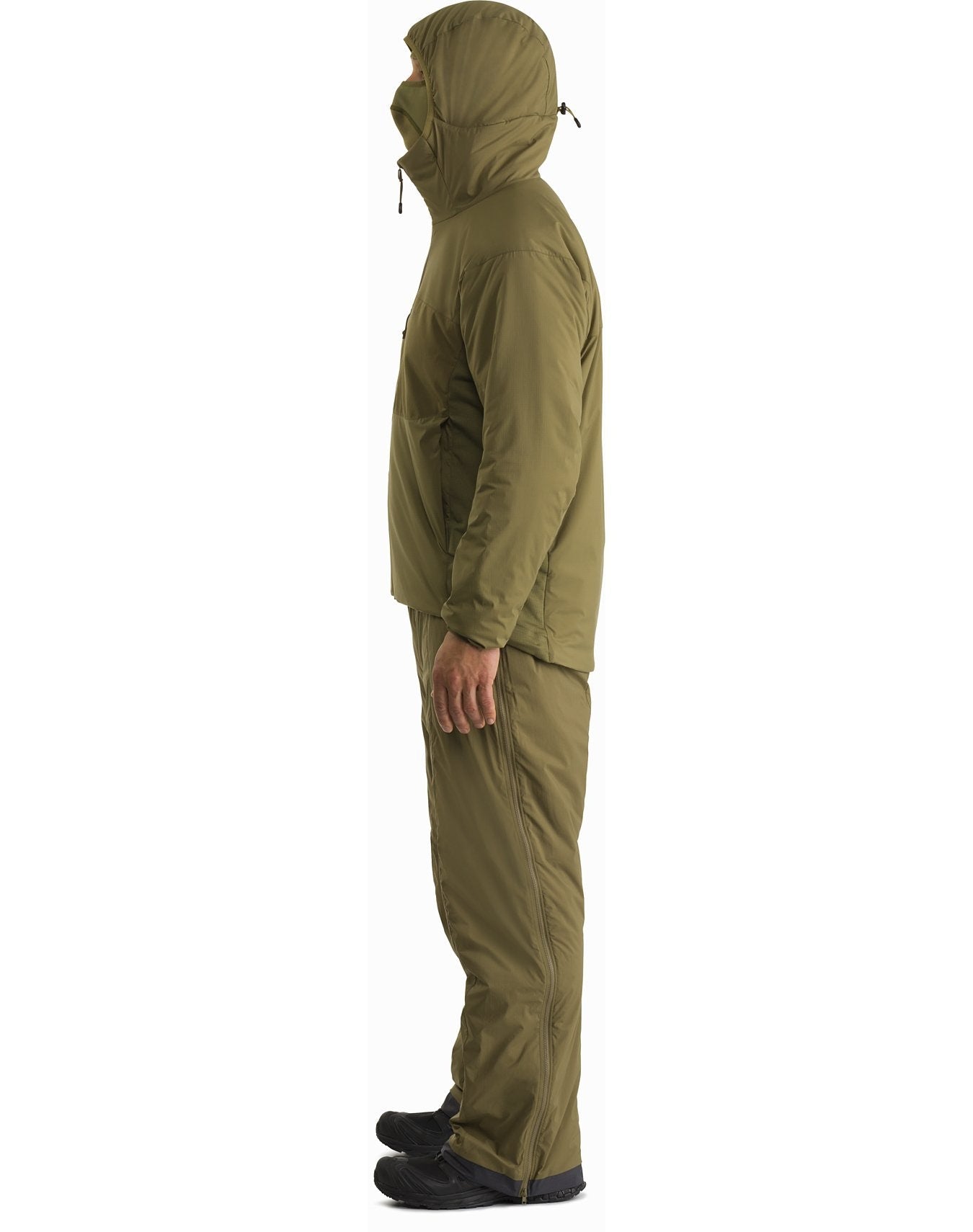 Eine Person steht im Profil vor einem weißen Hintergrund und trägt den ARC'TERYX LEAF Arc'teryx Atom Hoody LT Gen2.1 in Schwarz, gepaart mit einer passenden Hose und schwarzen Schuhen.