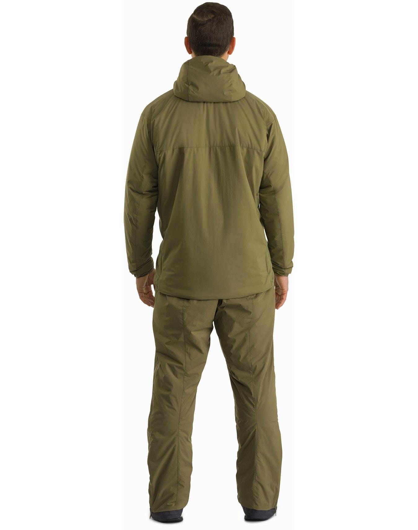 Eine Person blickt von der Kamera weg und trägt einen olivgrünen ARC'TERYX LEAF Arc'teryx Atom Hoody LT Gen2.1 - Crocodile und eine passende Hose vor einem schlichten weißen Hintergrund - perfekt für den Einsatz im Freien oder bei kaltem Wetter.