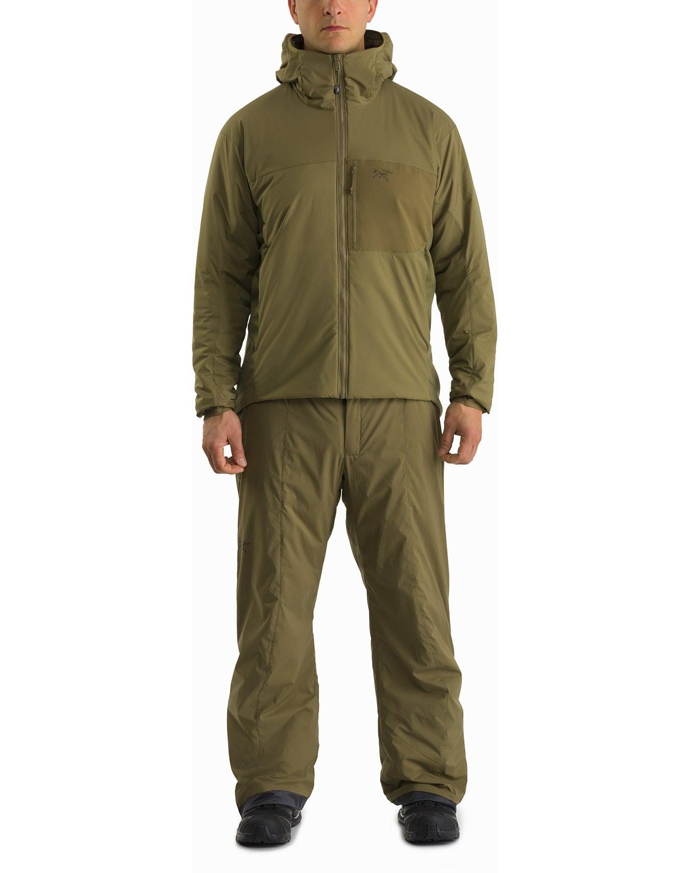 Eine Person steht mit Blickrichtung nach vorne in einem Ranger Green ARC'TERYX LEAF Arc'teryx Atom Hoody LT Gen2.1 mit passender Hose und schwarzen Schuhen vor einem schlichten weißen Hintergrund.