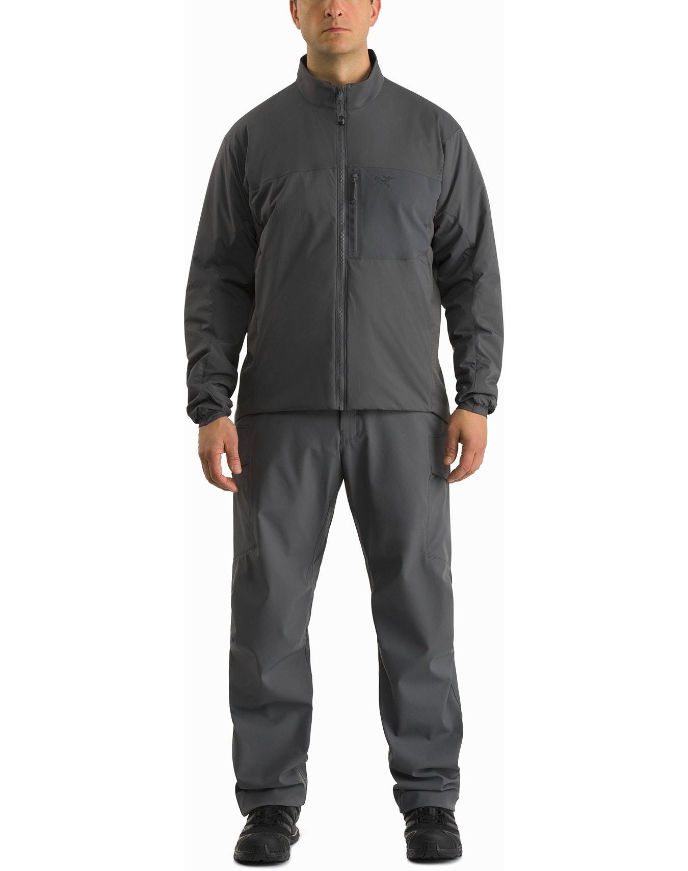 Eine Person blickt nach vorne und trägt die ARC'TERYX LEAF Arc'teryx Atom Jacket LT Gen2.1 in Ranger Green mit passender Hose und schwarzen Schuhen, die einen taktischen, wetterfesten Look vor einem schlichten weißen Hintergrund erzeugen.