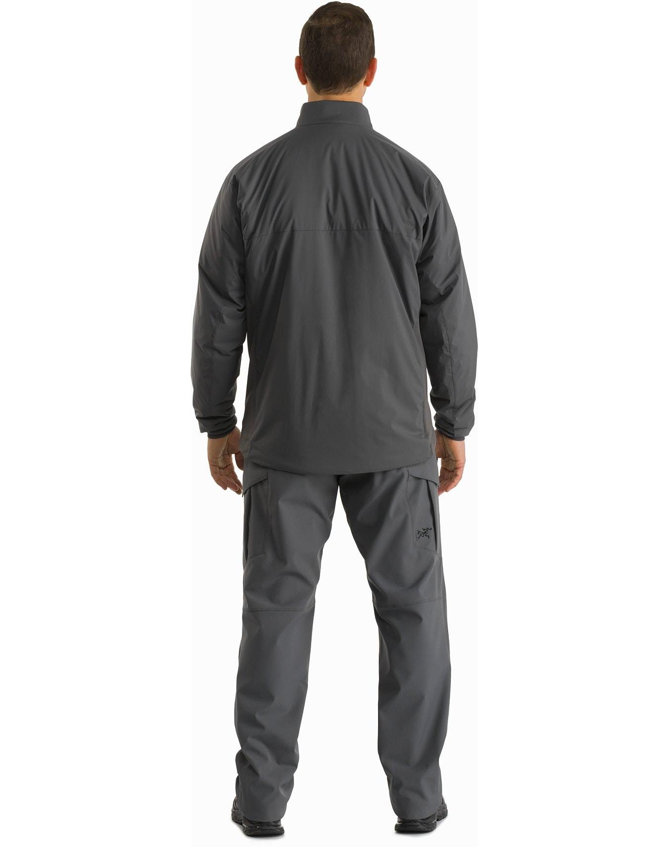 Eine Person blickt von der Kamera weg und trägt die ARC'TERYX LEAF Arc'teryx Atom Jacket LT Gen2.1 in Ranger Green mit passender POLARTEC Power Stretch Hose, geeignet für Outdoor- oder Arbeitsbekleidung, vor einem schlichten weißen Hintergrund.