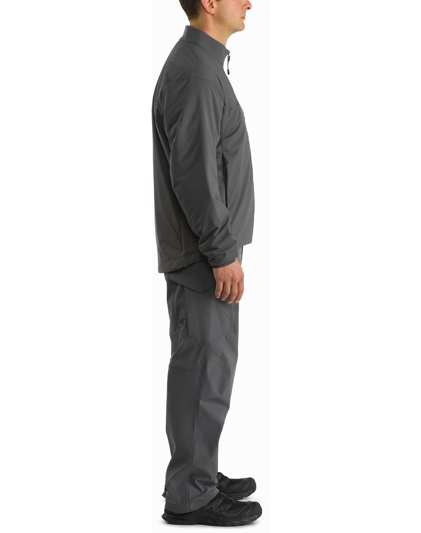 Eine Person in Profilansicht trägt eine ARC'TERYX LEAF Arc'teryx Atom Jacket LT Gen2.1 in Ranger Green mit passender Hose und schwarzen Schuhen, stehend vor einem schlichten weißen Hintergrund.