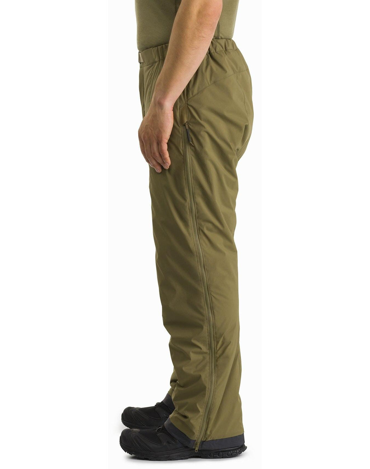 Seitenansicht der olivgrünen ARC'TERYX LEAF Arc'teryx Atom Pant LT Gen2 - Crocodile, mit durchgehendem Seitenreißverschluss und Oberschenkeltasche mit Reißverschluss, getragen mit schwarzen Stiefeln und einem passenden grünen Oberteil.