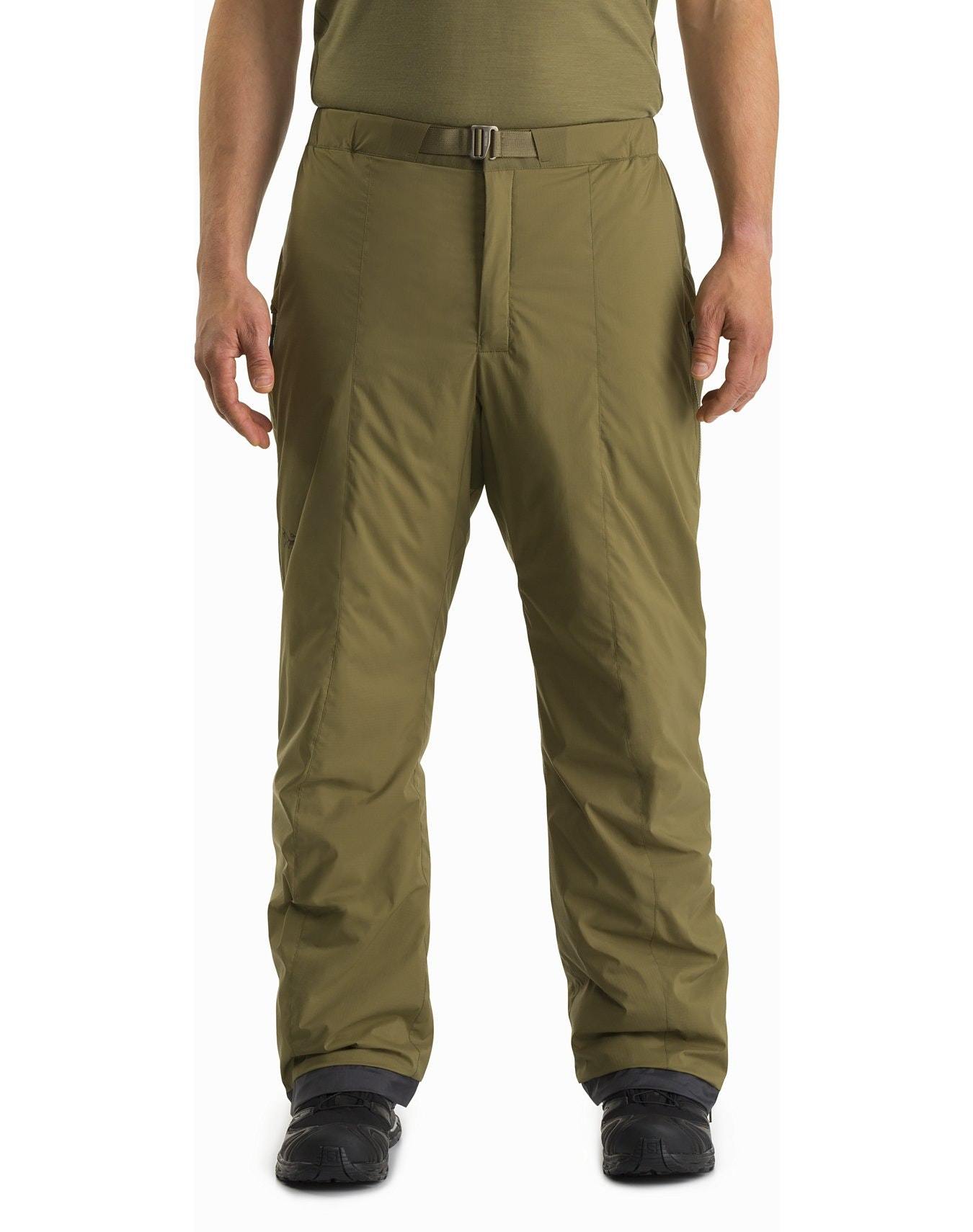 Eine Person, die eine schwarze ARC'TERYX LEAF Arc'teryx Atom Pant LT Gen2 Hose, ein grünes Hemd und schwarze Stiefel trägt, steht mit dem Gesicht nach vorne, so dass nur der untere Teil des Oberkörpers und die Beine sichtbar sind.