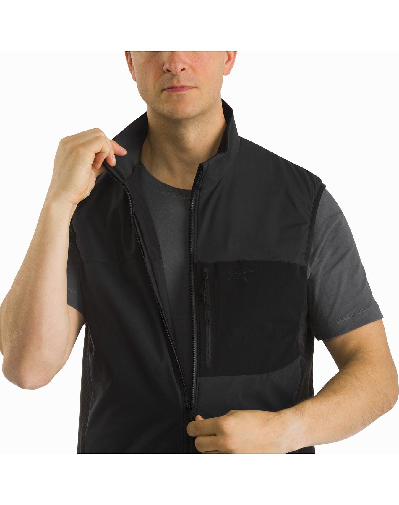 Ein Mann, der ein kurzärmeliges dunkles T-Shirt trägt, schließt den Reißverschluss einer ARC'TERYX LEAF Arc'teryx Atom Vest LT Gen2.1 - Black. Das Bild ist oben am Kopf und in der Mitte der Brust abgeschnitten und hat einen einfachen weißen Hintergrund.