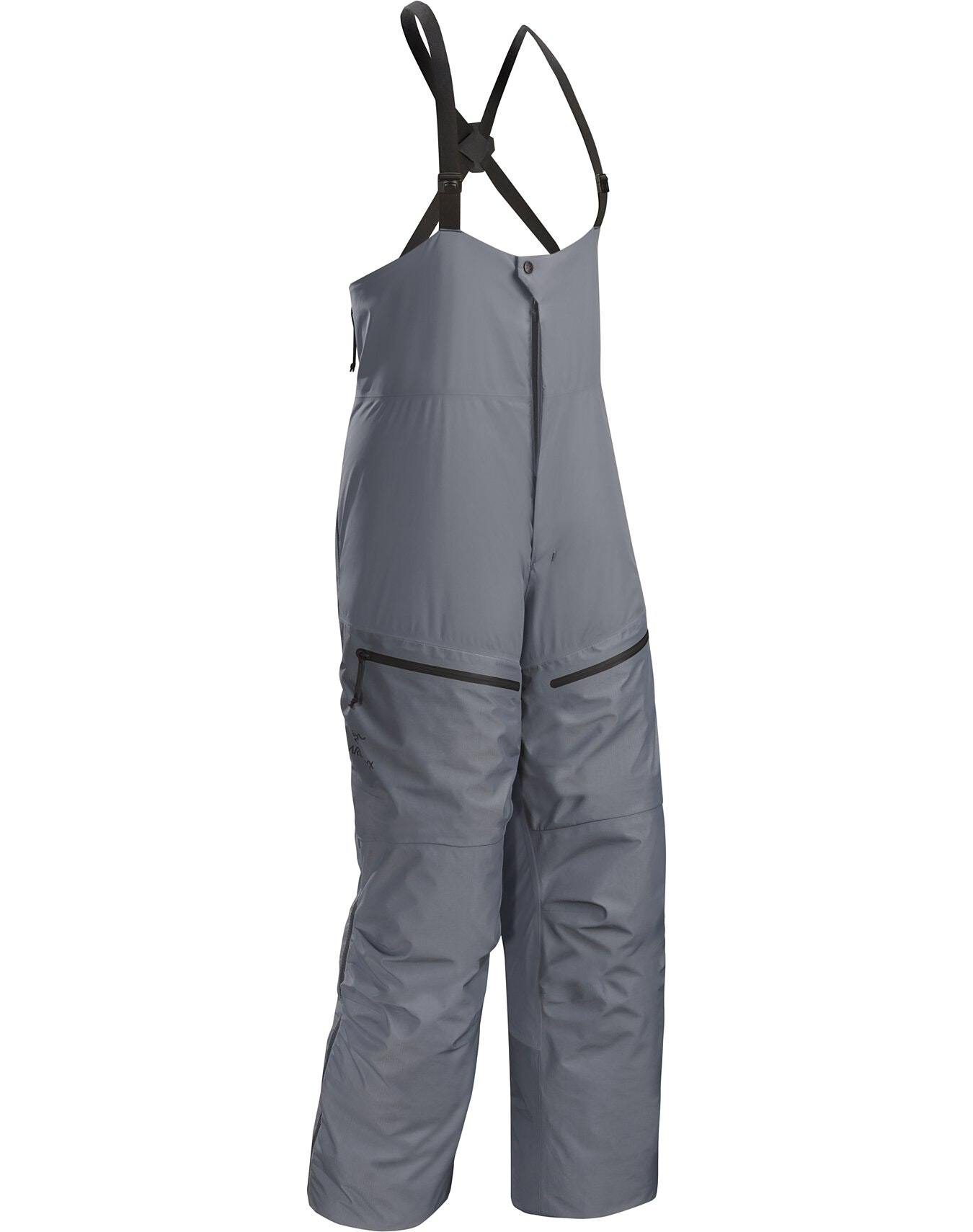 Die ARC'TERYX LEAF Arc'teryx Cold WX Bib Pant SVX Men's - Harrier ist eine grau isolierte Latzhose mit verstellbaren schwarzen Trägern, Frontreißverschluss, zwei Oberschenkeltaschen mit Reißverschluss, lockerer Passform und verstärkten Knien.