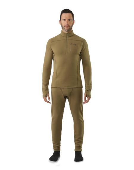 Ein Mann in einem olivgrünen Thermo-Oberteil und einer angepassten ARC'TERYX LEAF Arc'teryx Cold WX Bottom SV - Crocodile Hose mit schwarzen Socken, hergestellt aus Polartec Power Stretch, steht vor einem schlichten weißen Hintergrund.