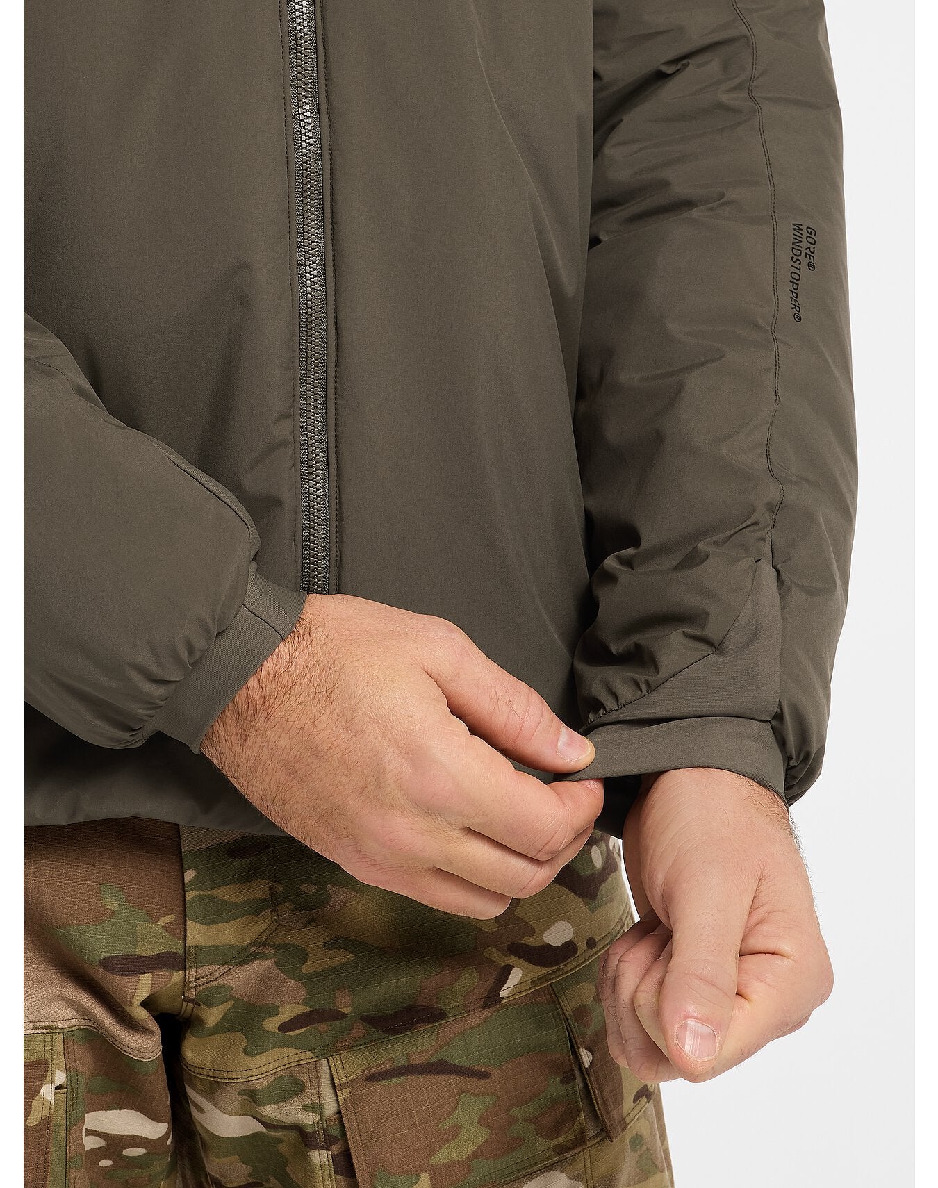 Nahaufnahme eines Mannes, der die ARC'TERYX LEAF Arc'teryx Cold WX Jacket LT Gen2.1 in Schwarz mit Isolierung und Frontreißverschluss trägt, gepaart mit einer Camouflage-Hose. Der Fokus liegt auf den Ärmelbündchen und den Torso-Details der Jacke.