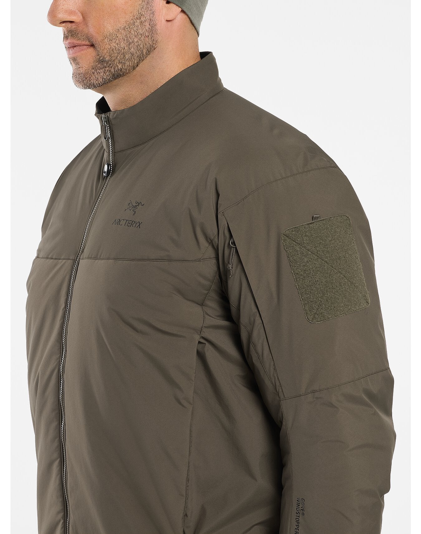 Der Mann trägt die ARC'TERYX LEAF Cold WX Jacket LT Gen2.1 in Crocodile mit CLIMASHIELD Isolierung, durchgehendem Reißverschluss, Stehkragen, Ärmelaufnäher mit Klettverschluss, GORE WINDSTOPPER Label und seitlicher Brusttasche mit Reißverschluss.