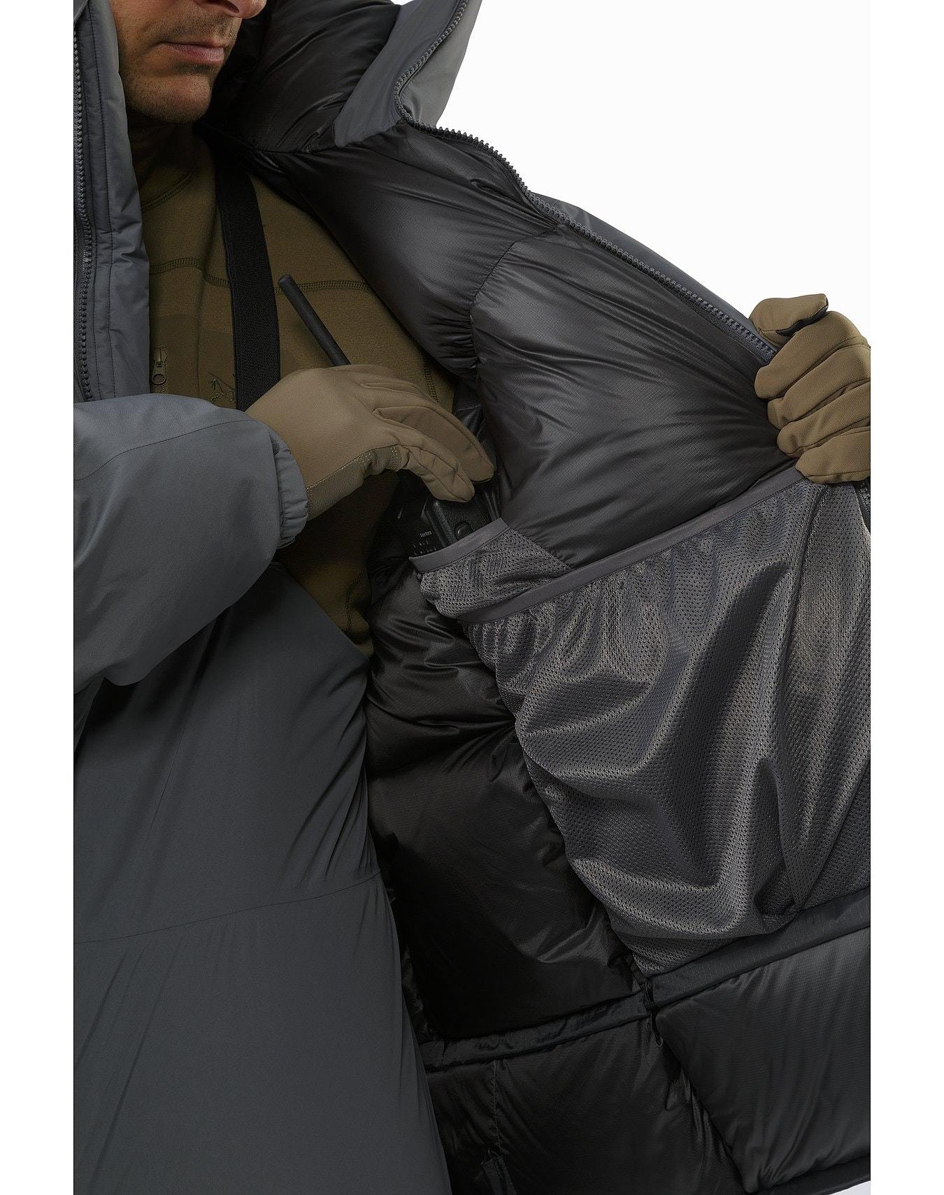 Eine behandschuhte Hand öffnet den ARC'TERYX LEAF Arc'teryx Cold WX Parka SVX - Wolf und gibt den Blick auf das isolierte Futter und die Netztaschen frei - die wichtigsten Merkmale dieser daunenisolierten Herrenjacke mit GORE-TEX Schutz.