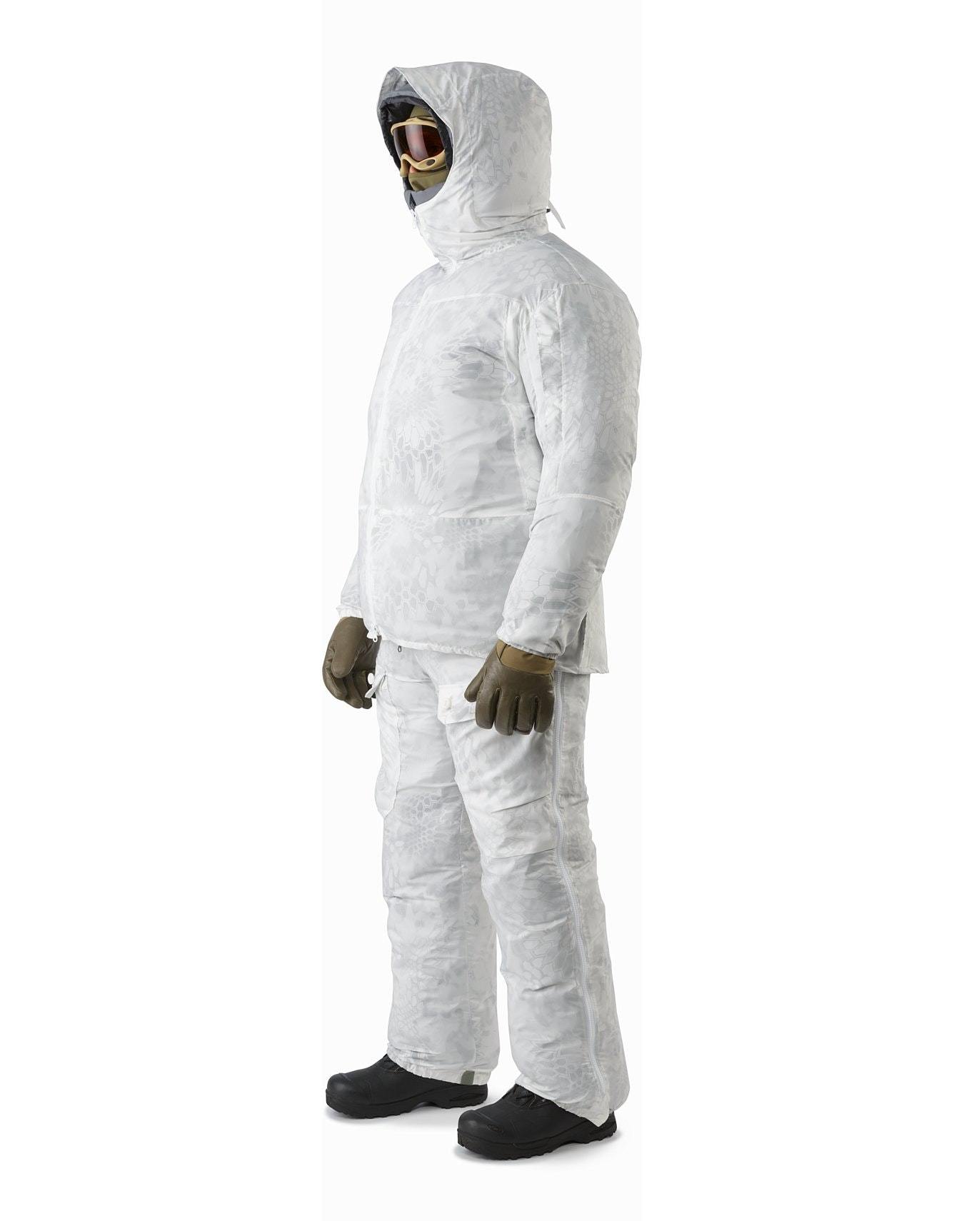 Eine Person trägt den ARC'TERYX LEAF Arc'teryx Cold WX Parka SVX - Wolf, gepaart mit braunen Handschuhen, schwarzen Stiefeln und einer Skibrille, alles vor einem schlichten weißen Hintergrund.