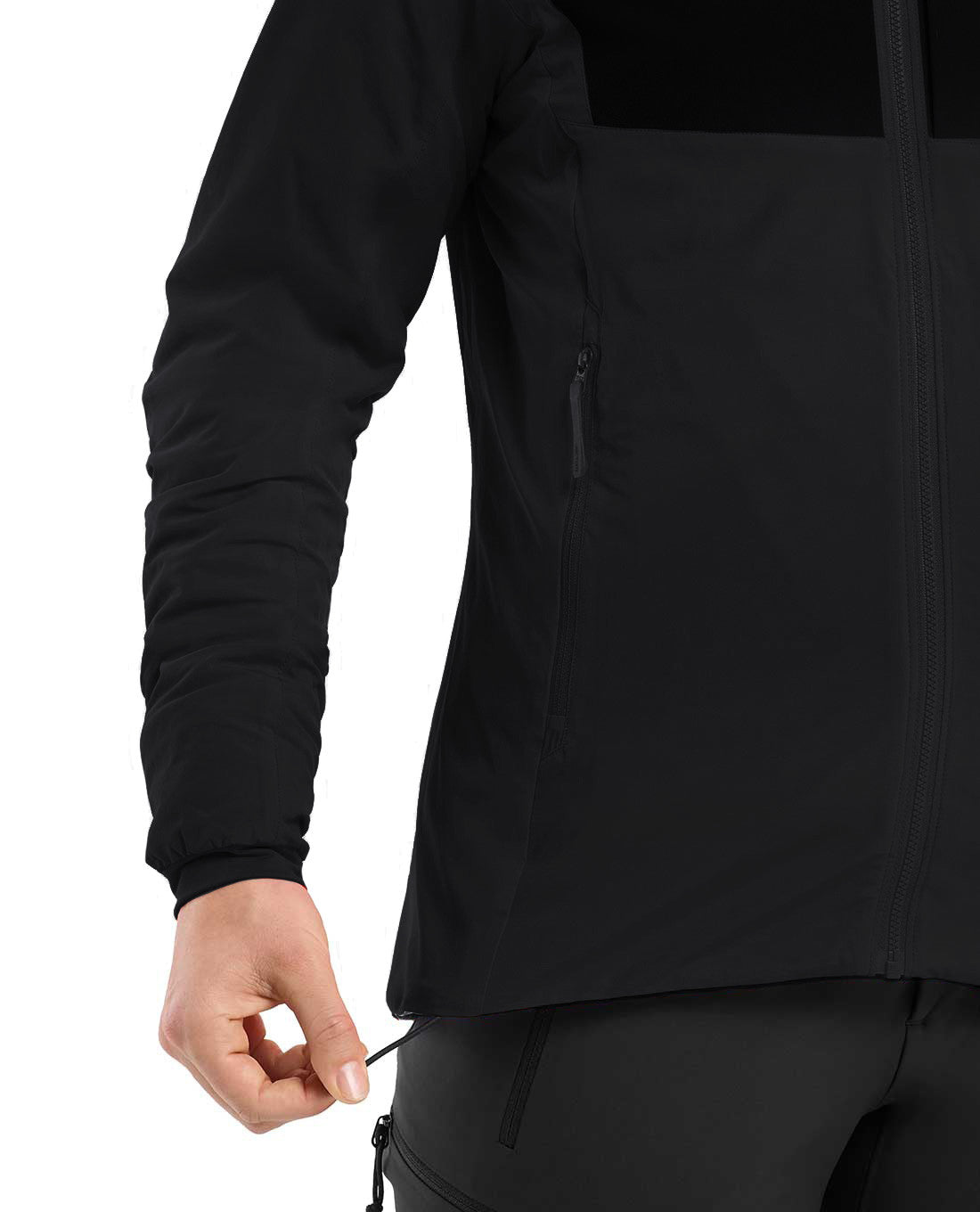 Eine Person, die ein schwarzes ARC'TERYX PRO Arc'teryx Practitioner AR Hoody Women's - Carbon Copy trägt, zieht mit der linken Hand am Saumkordelzug. Nur der untere Teil dieses atmungsaktiven Midlayers und ein Teil eines Arms erscheinen vor einem weißen Hintergrund.