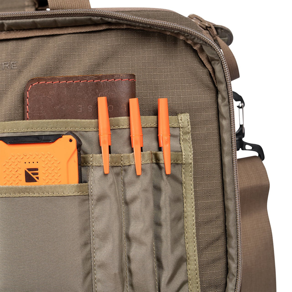 Eine Nahaufnahme der EBERLESTOCK Executive Brief Vordertasche aus 500D Cordura zeigt drei orangefarbene Stifte, ein Lederportemonnaie und ein orangefarbenes robustes Gerät, die ordentlich in einzelnen Fächern untergebracht sind.
