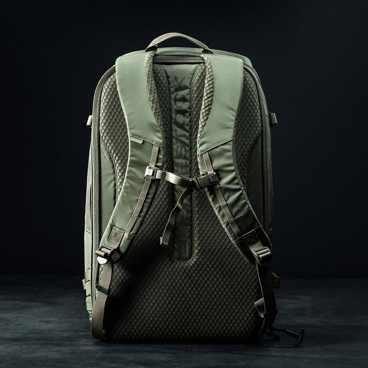 Der EBERLESTOCK Fade Adapt taktische Rucksack, hier von hinten in Grün, verfügt über gepolsterte Schultergurte, einen Brustgurt, eine ausklappbare Scheide und eine strukturierte Rückenplatte auf dunklem Grund.