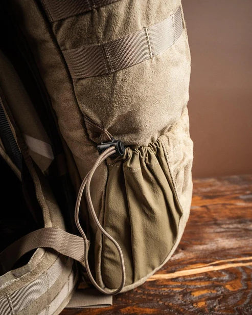 Nahaufnahme des EBERLESTOCK X2 - Bergrucksacks (40L), die eine Seitentasche mit elastischem Kordelzug und Kunststoffknebel auf einer Holzoberfläche zeigt. Sein robustes Material macht ihn ideal für Outdoor-Abenteuer.