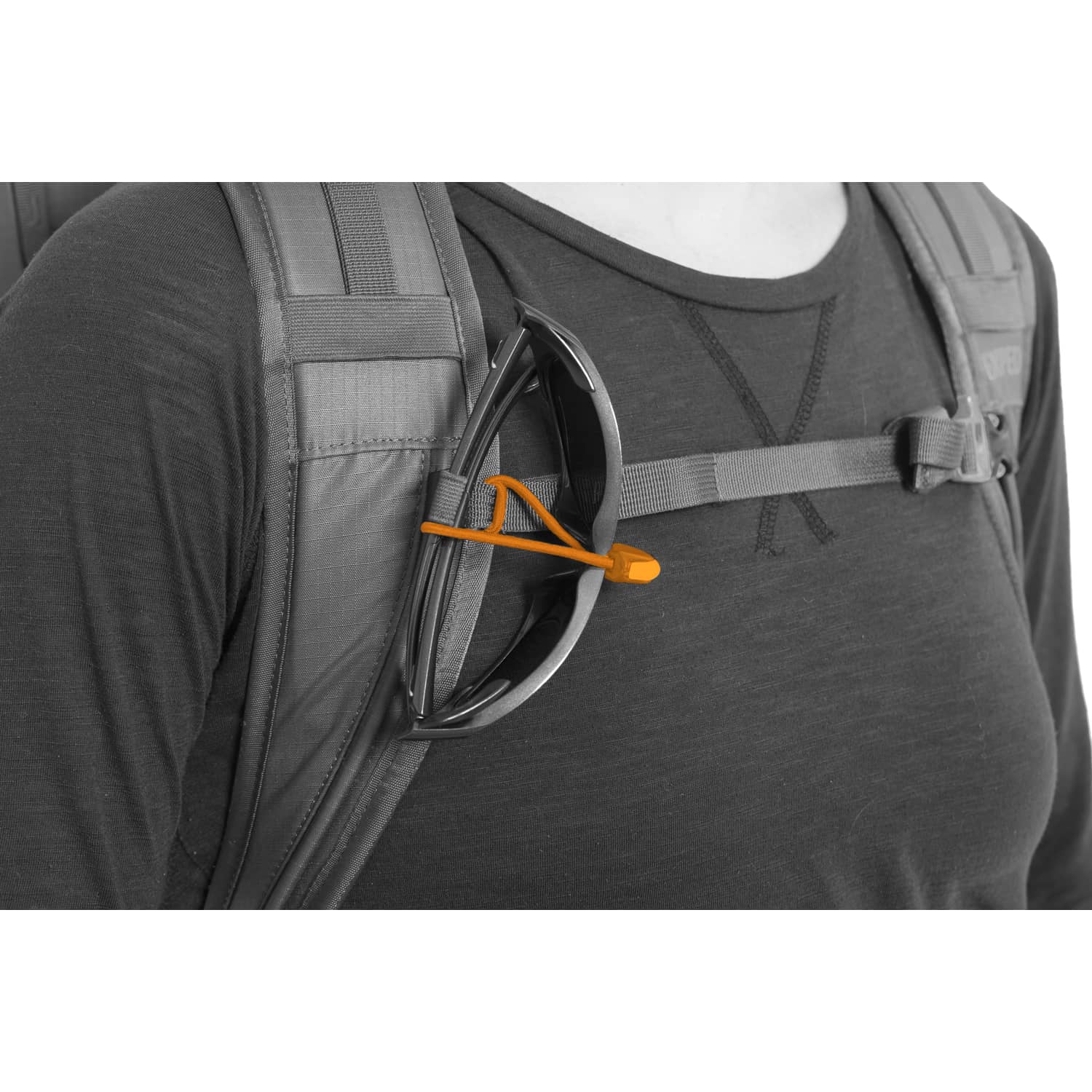 Eine Person mit einem EXPED Rucksack Verglas 30 mit grauem Schulterriemen und orangefarbener Sonnenbrille, bekleidet mit einem dunklen langärmeligen Hemd, bereit für Bergtouren.