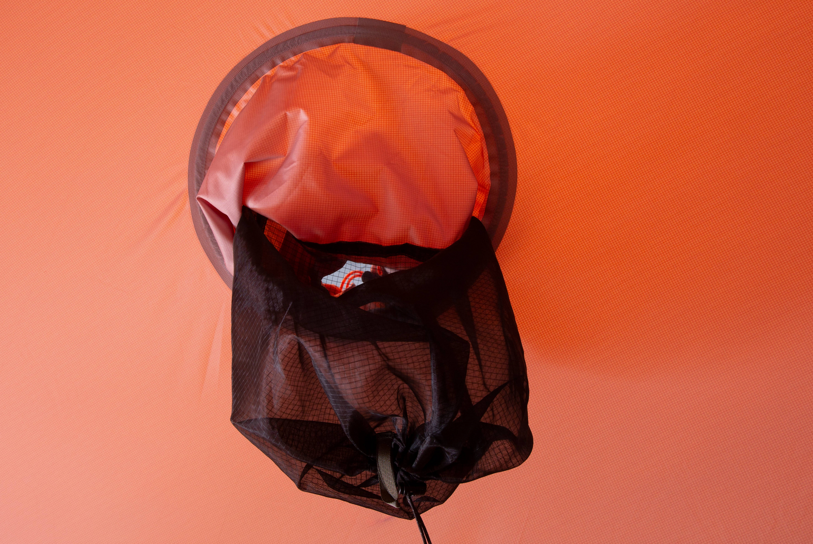 An der Innenwand des orangefarbenen EXPED Zelt Polaris ist eine schwarze Netztasche angebracht, über der sich die runde Zeltöffnung befindet, die teilweise geöffnet ist - ideal, um in jedem Expeditionszelt Ordnung zu halten.