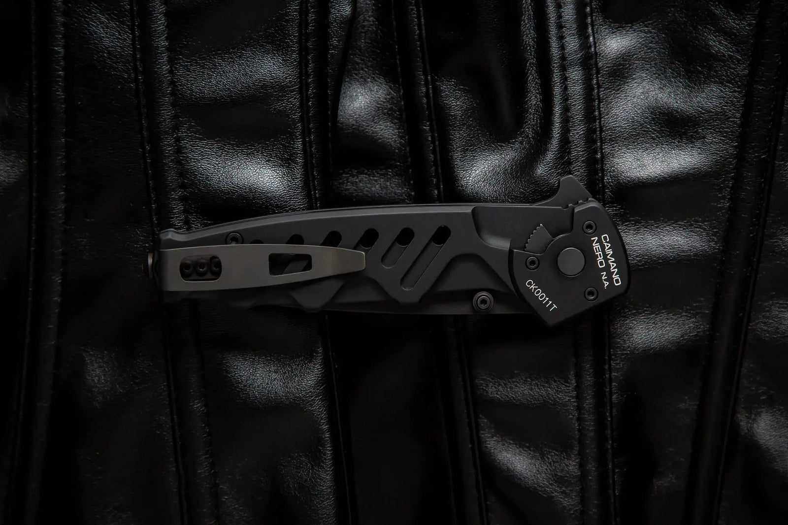 Ein EXTREMA RATIO Extrema Ratio Messer Caimano Nero N.A. Klapptaschenmesser mit Clip und kantigem schwarzem Design liegt geschlossen auf glänzendem schwarzem Leder mit vertikaler Naht.