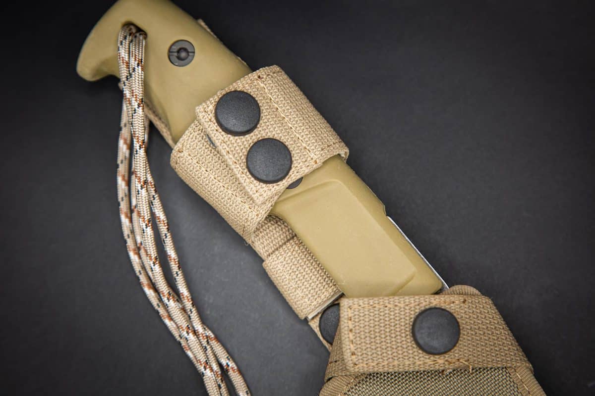 Das EXTREMA RATIO Messer Kreios Expedition, ein hellbraunes taktisches Messer mit Paracord-Lanyard, ist teilweise in einer passenden Stofftasche mit Druckknopfverschluss auf dunklem Hintergrund untergebracht - perfekt für den rauen Expeditionseinsatz.