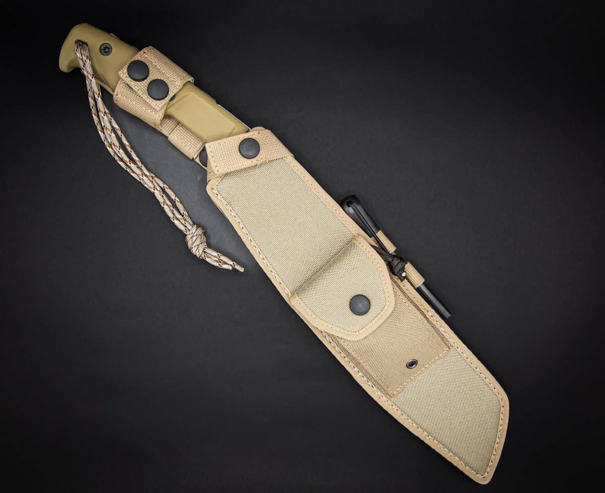 Das EXTREMA RATIO Messer Kreios Expedition, ein taktisches Messer mit feststehender Klinge, olivgrünem Griff und Paracord-Lanyard, wird in einer hellbraunen Nylonscheide mit Schnappverschlüssen und Feuerstarterstab geliefert.