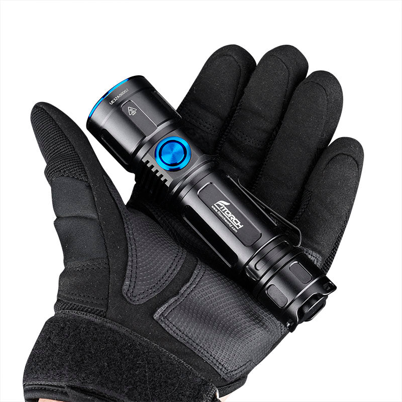 Eine behandschuhte Hand hält die FITORCH Fitorch Taschenlampe EC30, eine kompakte schwarze Taschenlampe mit blauen Akzenten, die ihr robustes Design vor einem schlichten weißen Hintergrund hervorhebt.