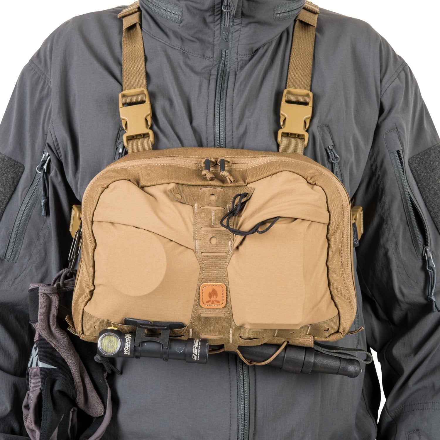 Der HELIKON-TEX Helikon-Tex Chest Pack Numbat® in Schwarz wird über einer grauen Jacke getragen. Er verfügt über Schnallenriemen, elastische Taschen, einen Logoaufnäher aus Leder, eine an der unteren Schiene befestigte Taschenlampe und ist MOLLE-kompatibel für Vielseitigkeit.