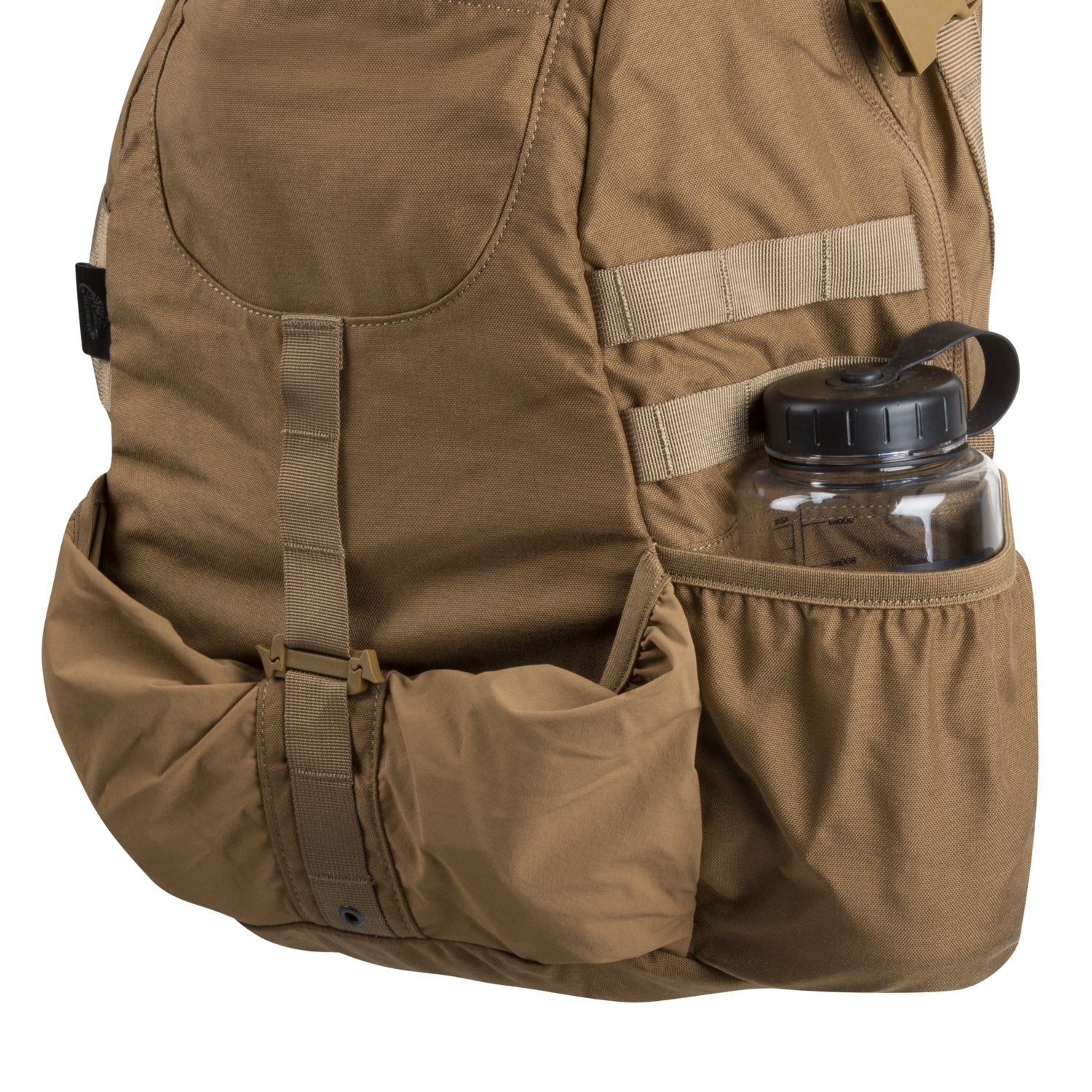 Eine Nahaufnahme des HELIKON-TEX Raider Backpack®, eines coyotefarbenen Rucksacks mit einer großen Vordertasche, beigen Trägern, Nähten, einer durchsichtigen Wasserflasche mit schwarzem Deckel in der Seitentasche und dem funktionellen Versatile Insert System.