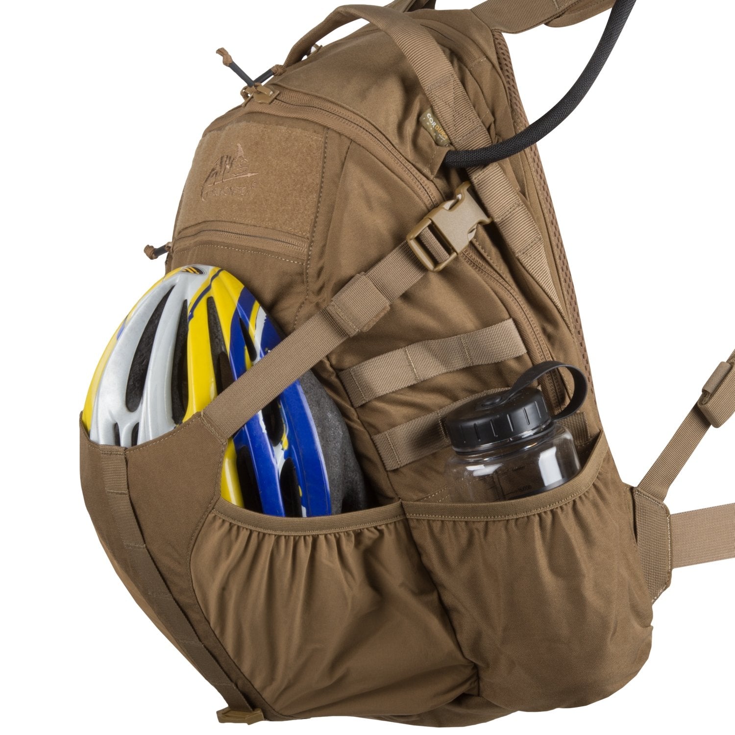 Der braune Helikon-Tex Raider Backpack® von HELIKON-TEX mit Seitentaschen bietet Platz für einen weißen, gelben und blauen Fahrradhelm und eine klare Wasserflasche. Sichtbare Riemen und Reißverschlüsse unterstreichen sein vielseitiges Einschubsystem für einfache Organisation.